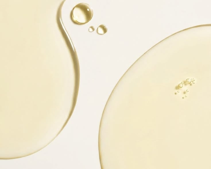 Close-up of a liquid droplet on a light beige background
